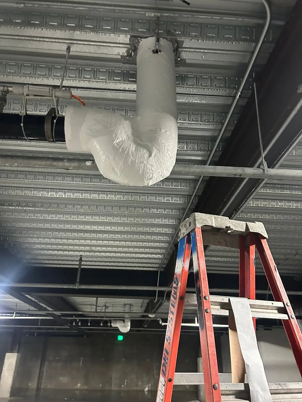 Insulated piping wrapped at ceiling penetration with fiberglass jacketing