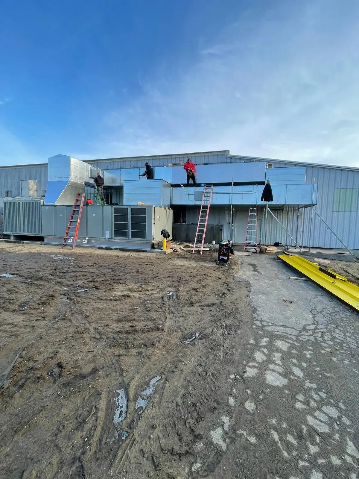 Crew installing insulated rooftop ductwork on new commercial construction