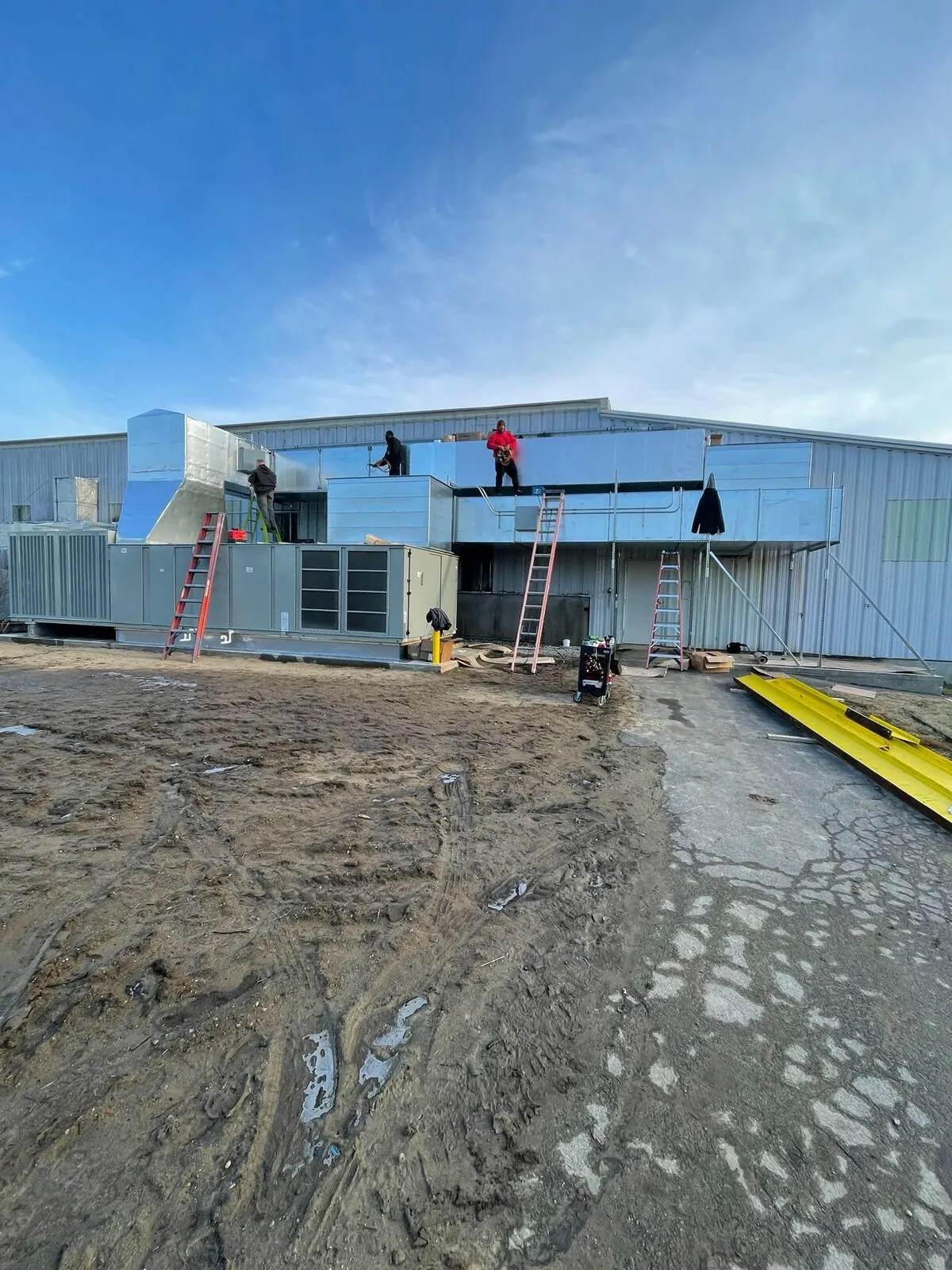 Crew installing insulated rooftop ductwork on new commercial construction
