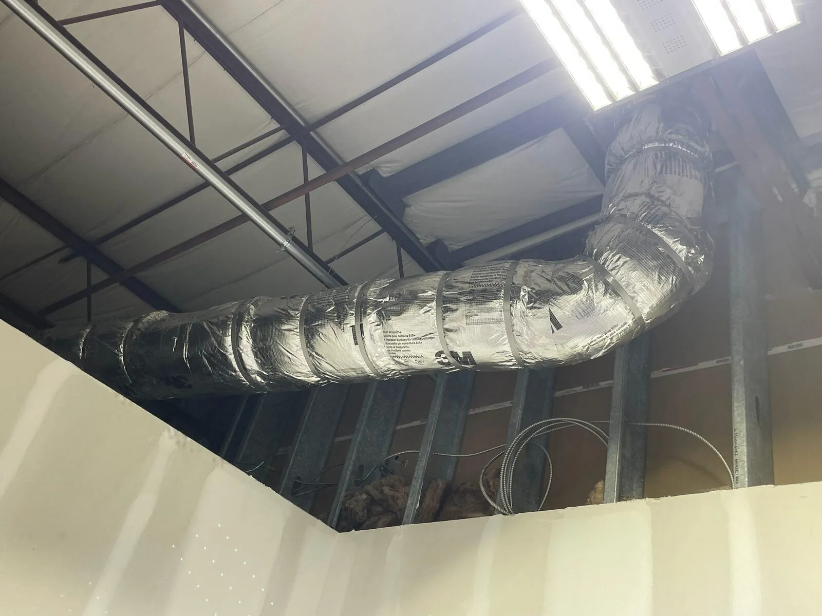 3M duct-wrapped HVAC supply line with insulated elbow at structural ceiling