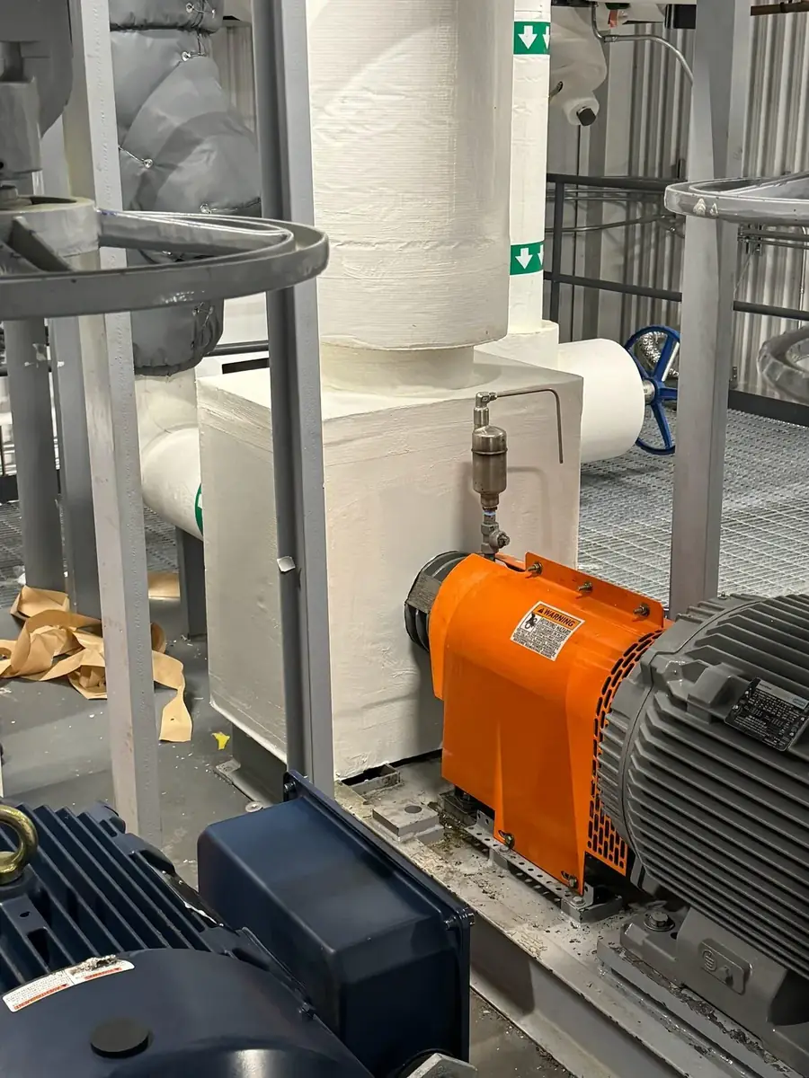 Master craftsman wrapping precision aluminum jacketing on insulated steam piping — Julius Mechanical Insulation