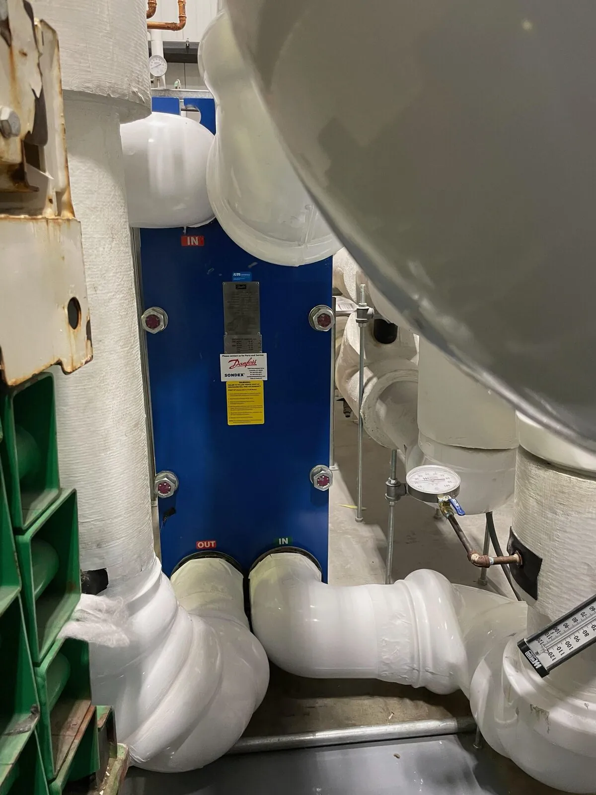 Danfoss heat exchanger surrounded by insulated PVC-jacketed process piping
