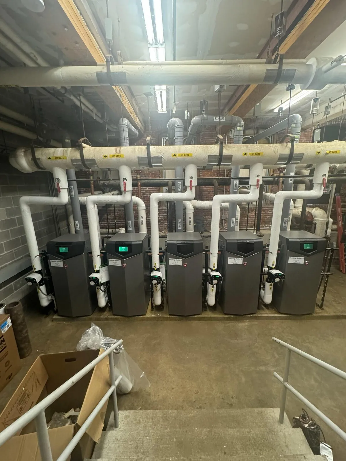 Boiler bank with insulated overhead hot water main and individual exhaust risers