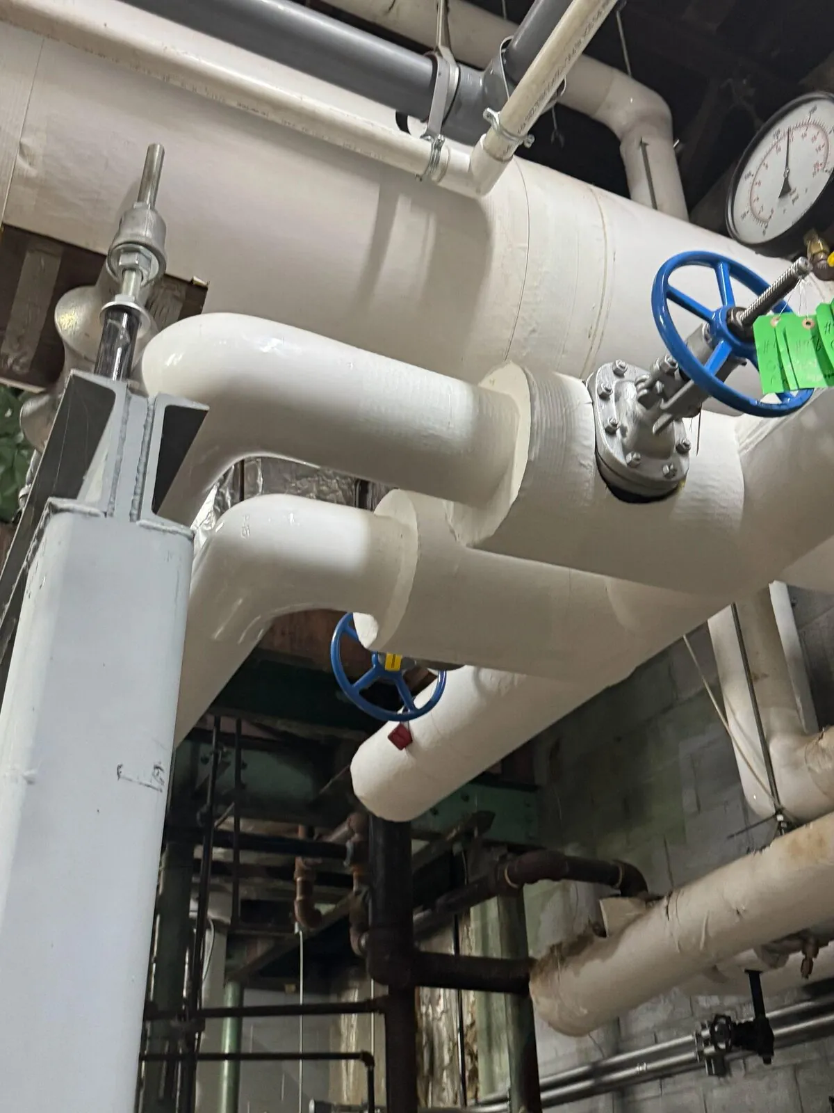 Insulated white piping run with isolation valves at boiler manifold
